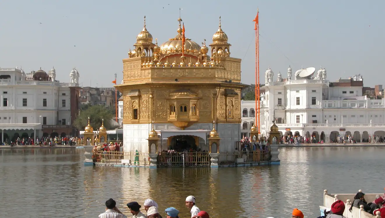 Rear east-facing view of Sri Harmandir Sahib across the Amrit Sarovar with devotees on the Parikrama, Amritsar, Punjab, India